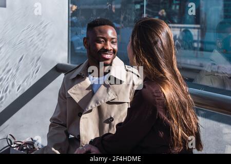 Un couple multiethnique plein de style dans des tenues élégantes banc sur la gare routière en ville Banque D'Images