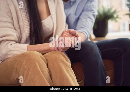 Couple multiracial assis sur un canapé dans le bureau du psychologue et tenir les mains pendant le rendez-vous de psychothérapie Banque D'Images