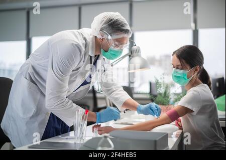 Une jeune femme est venue au laboratoire pour donner du sang d'une veine, une jeune assistante de laboratoire prend du sang Banque D'Images