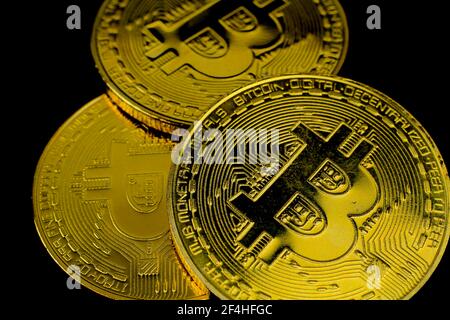 Trois bitcoins d'or sur fond noir. Photographie macro. Banque D'Images