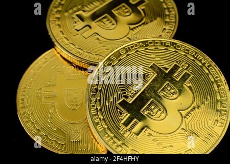 Trois bitcoins d'or sur fond noir. Photographie macro. Banque D'Images