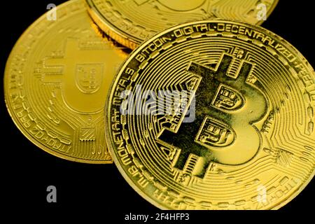 Trois bitcoins d'or sur fond noir. Photographie macro. Banque D'Images