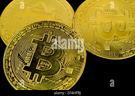 Trois bitcoins d'or sur fond noir. Photographie macro. Banque D'Images