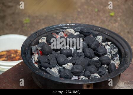 Briques de charbon de bois brûlant dans un fumeur de barbecue à la maison. Banque D'Images