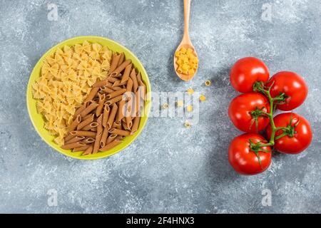 Deux sortes de pâtes crues sur plaque avec tomates Banque D'Images