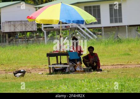 Les femmes sur le marché informel vendent leurs marchandises sur une table de fortune sous un parasol à l'extérieur de l'aéroport de Madang. Banque D'Images