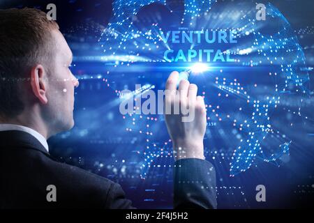 Concept commercial, technologique, Internet et réseau. Jeune homme d'affaires travaillant sur un écran virtuel de l'avenir et voit l'inscription: Venture capi Banque D'Images