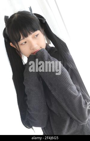 Portrait japonais école fille costume dormir et sourire en blanc chambre avec lit ton sur ton Banque D'Images