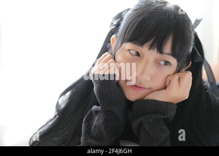 Portrait japonais école fille costume dormir et sourire en blanc chambre avec lit ton sur ton Banque D'Images