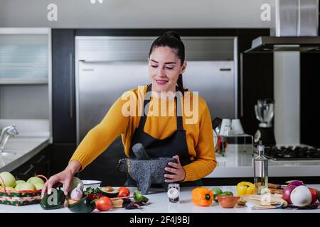 femme latine cuisant de la sauce mexicaine dans la cuisine à la maison À Mexico Banque D'Images