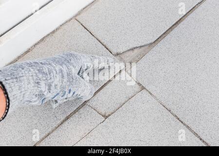 Main de l'ouvrier industriel dans les points de gants de construction sur fond de carreaux gris endommagés. Concept de rénovation. Banque D'Images
