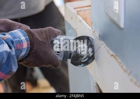 Rénovation à la maison de remplacement cloison sèche endommagée sur l'homme est en cours de coupe panneau de gypse avec outils électriques manuels Banque D'Images