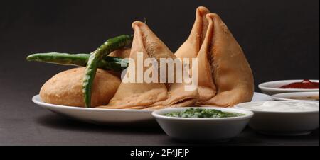 Kachori et samosa, des collations végétariennes servies avec des chutneys verts et tamarin. Banque D'Images