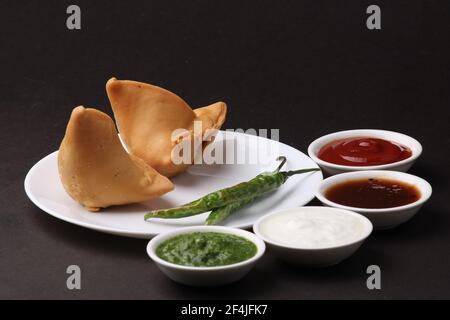 En-cas indien maison de samosa épicé et délicieux servi avec du chutney de tamarin vert. Banque D'Images