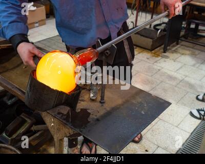 Souffleur de verre formant un beau morceau de verre. Un fer à souder en verre souffle et façonne une nouvelle pièce d'art Banque D'Images