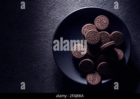 KRASNOYARSK, RUSSIE, 9 février 2020 : biscuits oreiro noirs en gros plan dans une assiette, vue du dessus. Arrière-plan texturé sombre. Banque D'Images