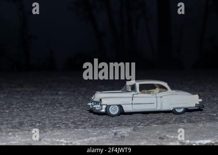 Jouet miniature Cadillac sur la route avec fond de forêt Banque D'Images