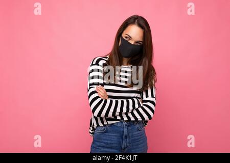 Jeune femme portant un masque anti-virus pour prévenir D'autres de l'infection corona COVID-19 et du cov 2 du SRAS ont été isolés sur fond rose Banque D'Images