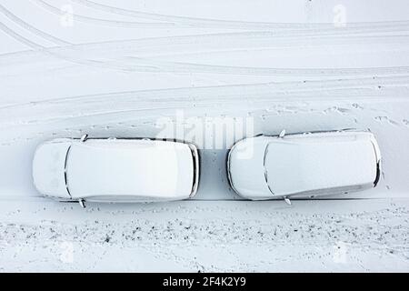 les voitures garées et la route sont recouvertes d'une couche de neige lisse, d'une vue de dessus, d'une photographie aérienne et de la journée d'hiver Banque D'Images