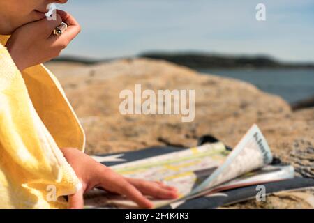 Femme se détendant sur la plage résoudre Crosswords pendant les vacances, jour ensoleillé Banque D'Images