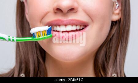 Antécédents en santé dentaire. Gros plan sur des dents saines et parfaites avec cette brosse à dents. Portrait d'une femme mignonne souriante tenant une brosse à dents. Femme souriante Banque D'Images
