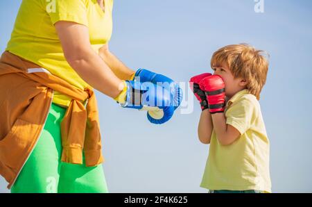 Le père forme sa boxe de fils. Petit sportif de garçon à l'entraînement de boxe avec entraîneur. Sportif entraîneur de boxe petit garçon dans des gants de boxe rouges Banque D'Images