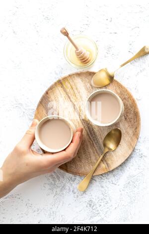 Deux tasses d'un latte de chai et une main tenant une tasse Banque D'Images