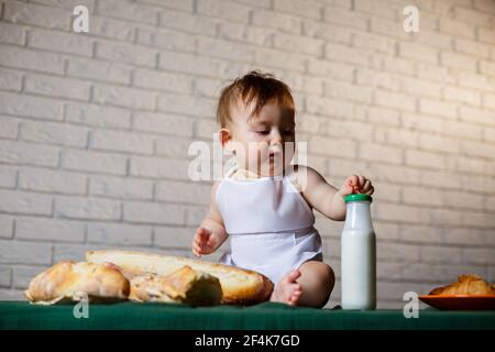 Petit garçon dans un chapeau et avec du pain. Petit enfant habillé comme un cuisinier dans la cuisine. Banque D'Images