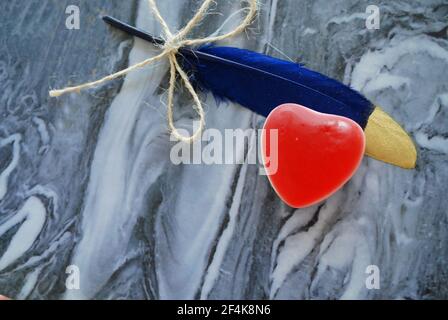 Gelée rouge en forme de coeur avec plume colorée isolée sur un magnifique fond, papier peint amour, Banque D'Images