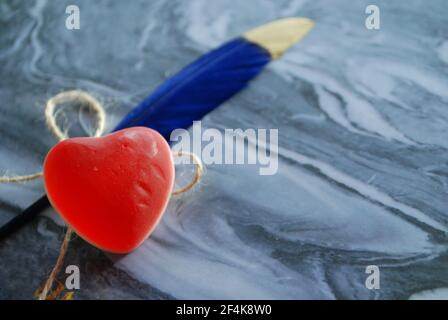 Gelée rouge en forme de coeur avec plume colorée isolée sur un magnifique fond, papier peint amour, Banque D'Images