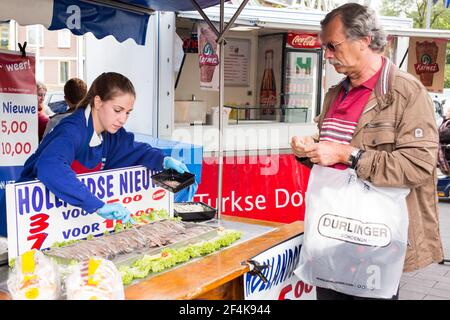 Tilburg, pays-Bas. Jeune femme adolescente travaillant à l'intérieur d'une cabine de poisson dans la région, Koningsplein, marché hebdomadaire du samedi. Pour cette jeune femme non identifiée, c'est une façon d'apprendre à travailler, à apprendre à gérer les finances et à compléter l'argent de poche de ses parents, ce qui augmente lentement dans sa propre indépendance. Banque D'Images