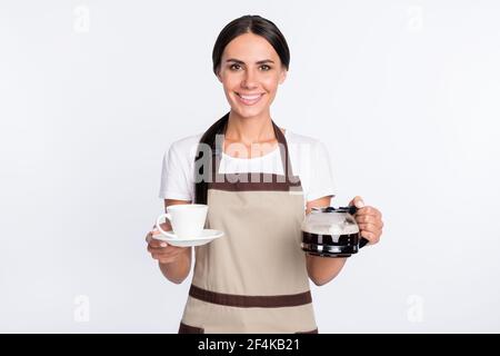 Photo de la femme optimiste de cheveux bruns avec le port de la tasse tablier de t-shirt isolé sur fond gris Banque D'Images