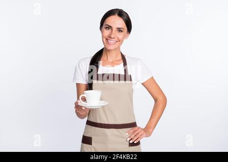 Photo de la femme optimiste de cheveux bruns avec le port de la tasse tablier de t-shirt isolé sur fond gris Banque D'Images