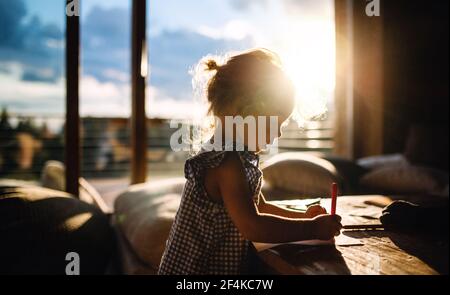 Petite fille dessin de photos dans une cabine en bois, concept de vacances dans la nature. Banque D'Images