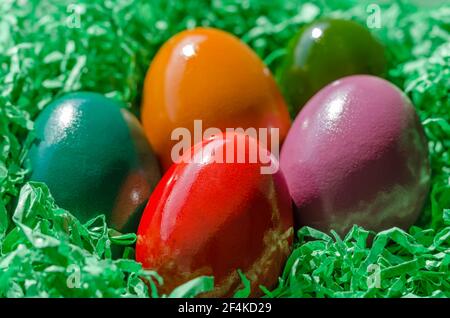 Nid de Pâques avec œufs Pascal multicolores. Oeufs de Pâques disposés dans un nid, fait de papier vert déchiqueté. Groupe d'œufs durs et colorés. Banque D'Images