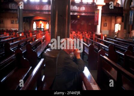 Un adorateur solitaire qui priait pour la paix dans l'ouest de Belfast 1998in L'église catholique St Paul dans la route des chutes Banque D'Images