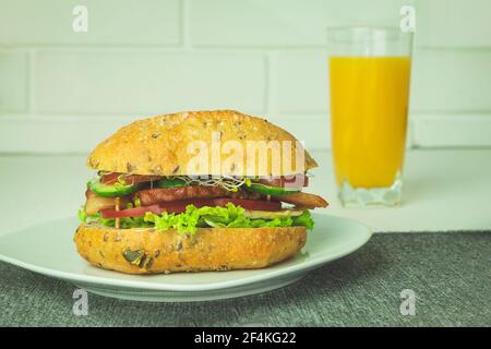 Hamburger sur une assiette blanche et jus d'orange. Sandwich appétissant sur une assiette comme arrière-plan avec espace pour le texte Banque D'Images