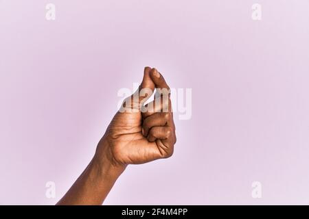 Bras et main de la femme d'âge moyen noire sur fond rose isolé tenant un espace vide avec le pouce, les affaires et la publicité Banque D'Images