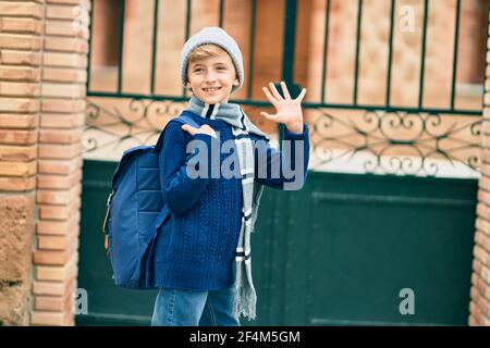 Adorable enfant blond étudiant disant Au revoir avec la main se mettre à l'école. Banque D'Images