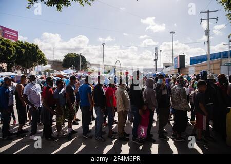 Tijuana, Mexique. 22 mars 2021. Les demandeurs d'asile attendent en file d'attente pour de la nourriture près de la place El Chaparral à Tijuana, au Mexique, le dimanche 21 mars 2021. Des centaines de demandeurs d'asile ont installé des tentes près du port d'entrée dans l'espoir de pouvoir demander l'asile aux États-Unis. Biden s'est engagé à prendre de nouvelles mesures pour faire face à l'afflux de migrants à la frontière depuis son arrivée au pouvoir. Photo par Ariana Drehsler/UPI crédit: UPI/Alay Live News Banque D'Images