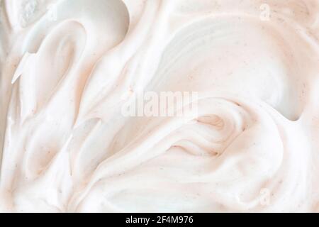 Texture crémeuse de mousse blanche aérée à gommage aux particules. Arrière-plan cosmétique doux avec lumière chaude teinte de la lumière. Banque D'Images