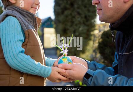 Entre les mains de l'enfant et de l'homme, il y a une terre miniature, une petite boule en forme de globe, d'où poussent les fleurs. Earth Eco Day concept, Environmental Educa Banque D'Images