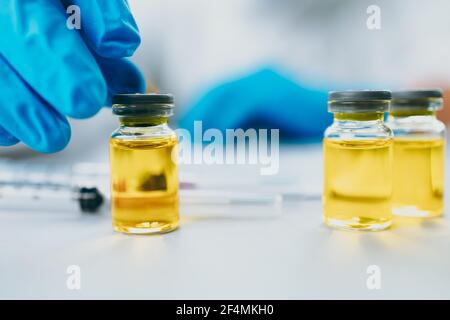 Le médecin vérifie et teste le vaccin en laboratoire et porte des gants médicaux, un équipement de protection individuelle ou un epi, un masque, des lunettes et un costume pour protéger le COVID-19 i. Banque D'Images