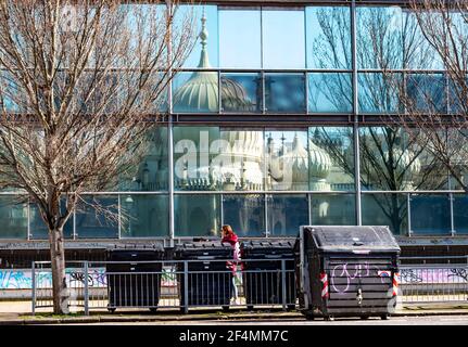 Brighton UK 22 mars 2021 - UN marcheur passe par les réflexions du Pavillon Royal de Brighton pendant le beau soleil chaud de printemps mais le temps beaucoup plus froid est prévu pour plus tard dans la semaine dans toute la Grande-Bretagne : crédit Simon Dack / Alamy Live News Banque D'Images