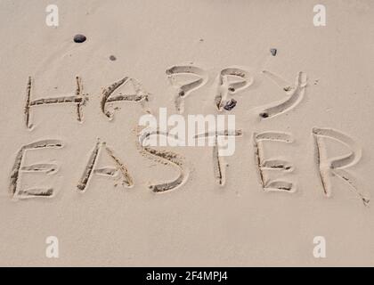 Joyeuses Pâques écrites dans le sable sur une plage de Norfolk. Banque D'Images