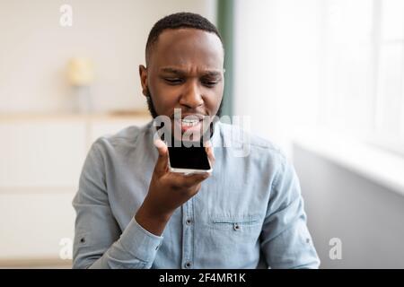 Black Business Guy utilisant le téléphone avec Voice Assistant dans le bureau Banque D'Images