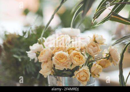 Image d'arrière-plan décolorée de belles roses pâles disposées en composition florale à l'atelier de fleuristes verts, espace de copie Banque D'Images
