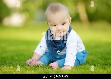 Mignon petit garçon de cinq mois apprendre à s'asseoir sans soutien. Bébé au sol. Adorable petit enfant essayant de s'asseoir seul. Banque D'Images