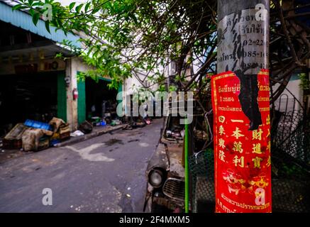 Un lampost recouvert d'une affiche rouge avec un script chinois doré se dresse à l'entrée d'une petite ruelle à Talat Noi, Bangkok, Thaïlande Banque D'Images