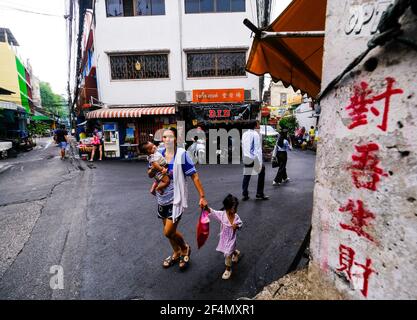 Une femme avec ses 2 petits enfants marche le long d'une route étroite à Talat Noi, Bangkok, Thaïlande Banque D'Images